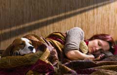 female and her dog sleeping in a bed together